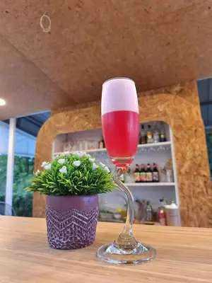 a glass of wine sitting on a table with a plant at PAN Beachfront Resort Krabi in Klong Muang Beach