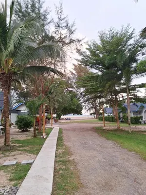a dirt road with palm trees and houses at PAN Beachfront Resort Krabi in Klong Muang Beach