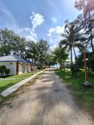 a road with palm trees on the side of a house at PAN Beachfront Resort Krabi in Klong Muang Beach
