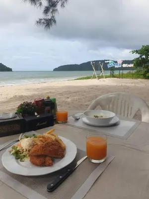 a table with a plate of food on the beach at PAN Beachfront Resort Krabi in Klong Muang Beach