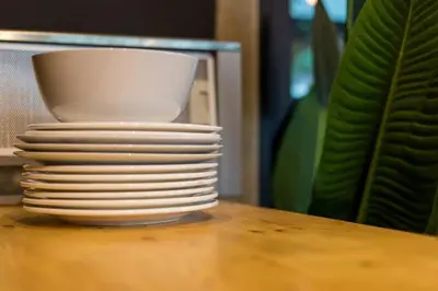 a stack of plates on a table next to a plant at 9BR Neverland Loft Pool Villa in Ban Saiyuan (1)