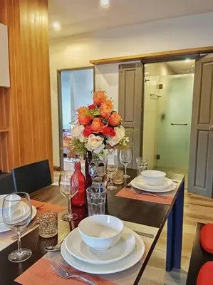 a dining room table with plates and a vase of flowers at Hill Myna Condo by Bcare - Two Bedrooms in Ban Thalat Choeng Thale