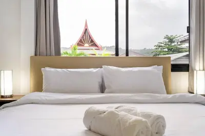 a bedroom with a large bed with a large window at Kamala - 2 BR Pool View Apartment in Kamala Beach