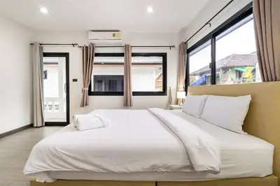 a large white bed in a room with windows at Kamala - 2 BR Pool View Apartment in Kamala Beach
