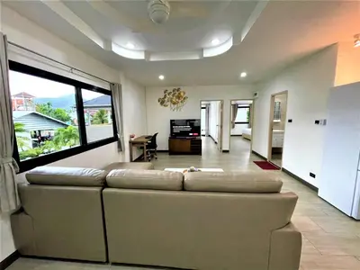 a living room with a couch and a large window at Kamala - 2 BR Pool View Apartment in Kamala Beach