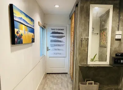 a hallway with a white door and a painting on the wall at Malai Maikhao Near Beach in Ban Mai Salae