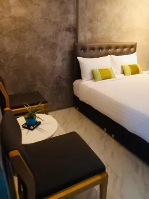 a bedroom with two beds and a chair and a table at Malai Maikhao Near Beach in Ban Mai Salae