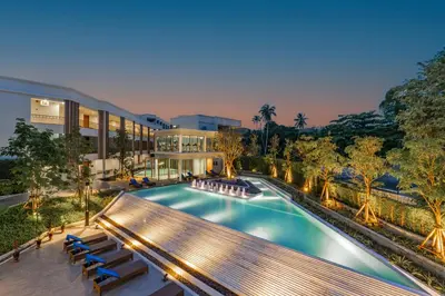 an outdoor swimming pool with a bench and a building at Bella Nara Phuket Naiyang Beach in Nai Yang Beach
