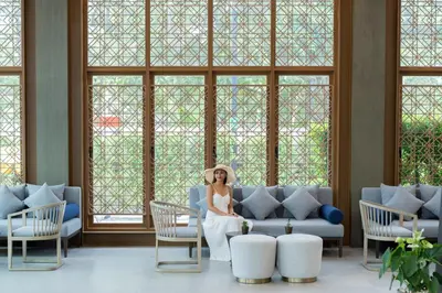 a bride sitting on a couch in a room with windows at Bella Nara Phuket Naiyang Beach in Nai Yang Beach