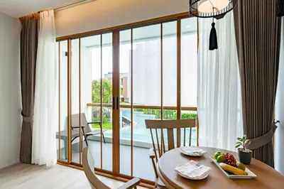 a room with a table and a large glass window at Bella Nara Phuket Naiyang Beach in Nai Yang Beach