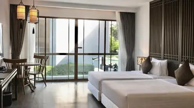 a hotel room with two beds and a balcony at Bella Nara Phuket Naiyang Beach in Nai Yang Beach