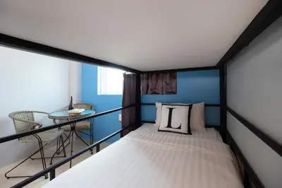 a small bedroom with a bed and a table at Bell Lifestyle Hostel Phuket in Nai Yang Beach