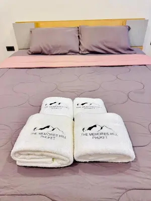 two white towels sitting on top of a bed at The Memories Hill Phuket in Thalang