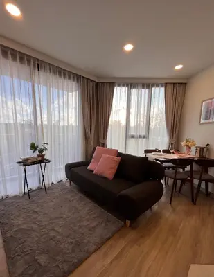 a living room with a black couch and a table at 1 Bedroom Sky Park corner in Bang Tao Beach