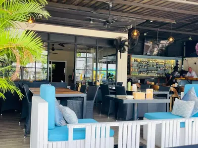 a restaurant with blue chairs and tables and a bar at New Breakers Hotel Rawai in Rawai Beach