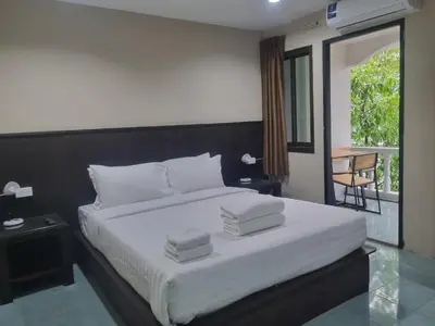 a bedroom with a white bed and a balcony at New Breakers Hotel Rawai in Rawai Beach