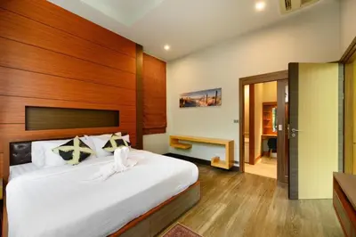 a bedroom with a large bed with a wooden headboard at Villa Pattara Rawai in Ban Saiyuan (1)