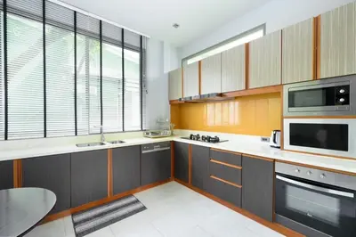 a kitchen with wooden cabinets and a microwave oven at Villa Pattara Rawai in Ban Saiyuan (1)