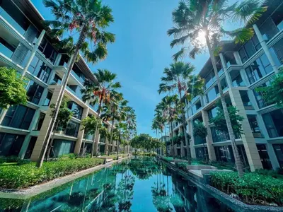 a canal with palm trees in front of a building at Baan Mai Khao apartments Phuket in Mai Khao Beach