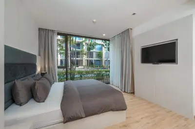 a bedroom with a large bed and a television at Baan Mai Khao apartments Phuket in Mai Khao Beach
