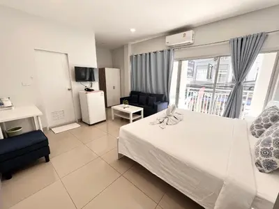a bedroom with a bed and a couch and a window at Cinderella Residence in Patong Beach