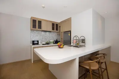 a kitchen with a white counter and two bar stools at Chic Design & Full Seaview 2BR Karon Condo 16C, near Beach in Karon Beach