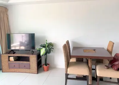 a dining room with a table and a tv at Spacious apartment at Kata Ocean View M11 in Kata Beach
