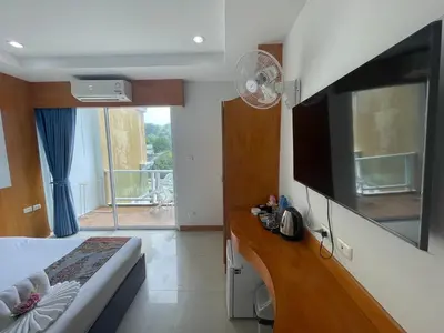 a bedroom with a large flat screen tv on the wall at T & C Hotel Patong Beach in Patong Beach