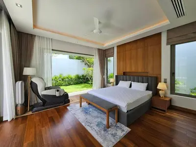 a bedroom with a bed and a chair and a window at Private pool villa 3 Bed, 3 Bath near airport in Phuket Town