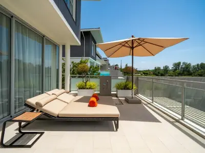 a patio with a couch and an umbrella on a building at ANGSANA Beachfront Residences apartment with pool in Laguna Phuket in Bang Tao Beach