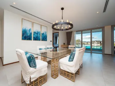 a dining room with a glass table and white chairs at ANGSANA Beachfront Residences apartment with pool in Laguna Phuket in Bang Tao Beach