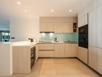 a kitchen with wooden cabinets and a counter top at ANGSANA Beachfront Residences apartment with pool in Laguna Phuket in Bang Tao Beach