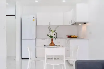 a white kitchen with a white table and white chairs at Patong Tower Brand New 1-Bedroom , Near Beach in Patong Beach