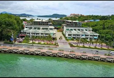 a large white building next to a body of water at Panwa Beach Side Beachfront in Panwa Beach
