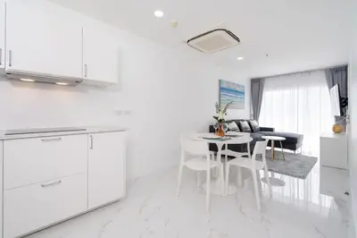 a kitchen with white cabinets and a table and chairs at Patong Tower 1-Bedroom , 200 meters from the Beach in Patong Beach
