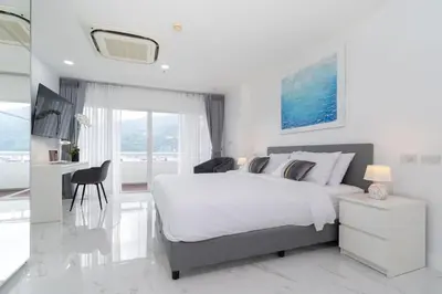 a white bedroom with a large bed and a desk at Patong Tower 1-Bedroom , 200 meters from the Beach in Patong Beach