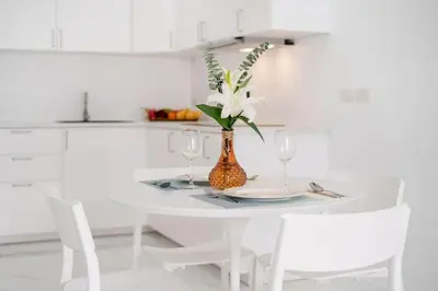 a white kitchen with a white table with a vase with flowers at Patong Tower 1-Bedroom , 200 meters from the Beach in Patong Beach