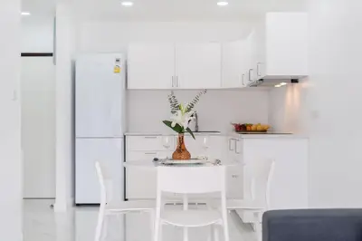 a white kitchen with a white table and chairs at Patong Tower 1-Bedroom , 200 meters from the Beach in Patong Beach