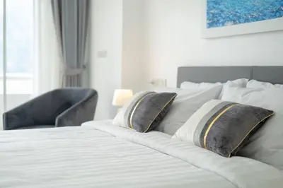 a bedroom with a bed with two pillows and a chair at Patong Tower 1-Bedroom , 200 meters from the Beach in Patong Beach