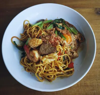 a white bowl of noodles with shrimp and vegetables at Pinpoint Hotel Phuket in Ban Pak Lak