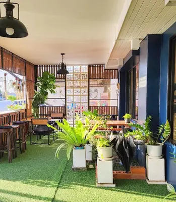 a restaurant with potted plants and tables and chairs at Pinpoint Hotel Phuket in Ban Pak Lak