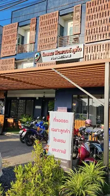 a sign in front of a building with motorcycles parked outside at Pinpoint Hotel Phuket in Ban Pak Lak