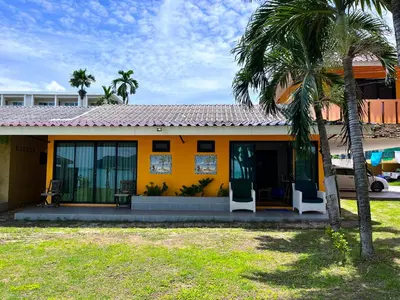 a yellow house with two palm trees in front of it at Secret Place in Panwa Beach
