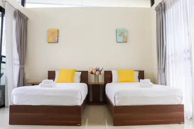 two beds in a room with white walls and yellow pillows at 3BDR Townhouse in Laguna Park in Bang Tao Beach