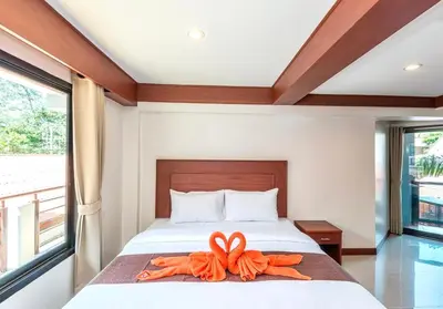 a bedroom with a bed with an orange ribbon on it at Kata Noi Bay Inn in Kata Beach