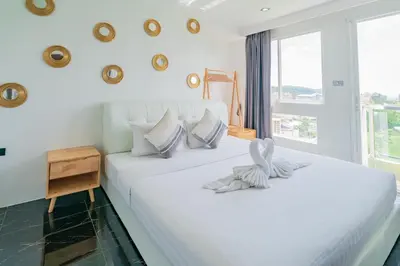 a white bed in a room with a window at Patong Diamond Hotel in Patong Beach