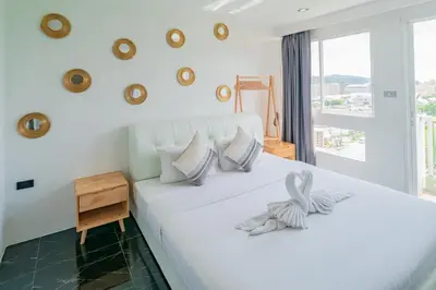 a bedroom with a white bed with a window at Patong Diamond Hotel in Patong Beach