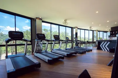 a gym with a row of treadmills and large windows at Modern Urban Living Kamala in Kamala Beach