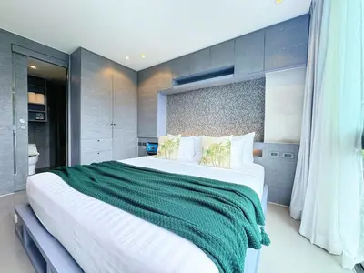 a bedroom with a large bed with a green blanket at Modern Urban Living Kamala in Kamala Beach