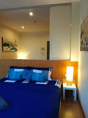 a blue bed in a room with a lamp at Hill Myna Condotel by Bcare - One Bedroom in Ban Thalat Choeng Thale